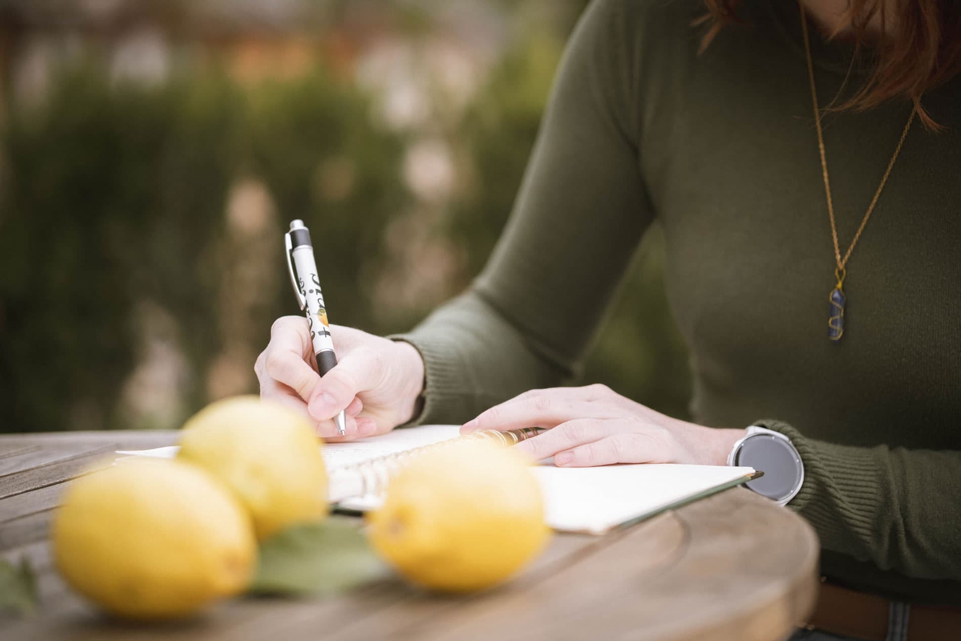 Texterin Julia schreibt in Notizbuch auf einer Bank im Freien in Südtirol